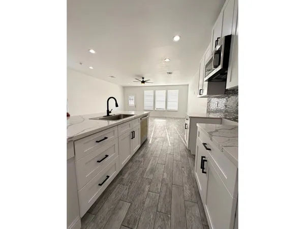 a view of a kitchen with kitchen island a sink stainless steel appliances and cabinets