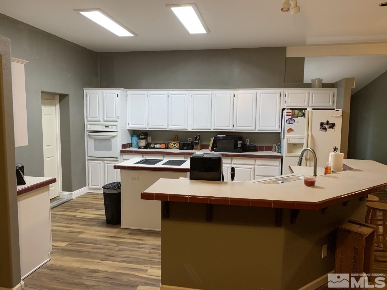 450 Reservoir Road Lovelock, NV 89419 - Photo 10 of 37 a kitchen with kitchen island a sink dishwasher a stove a microwave oven with white cabinets and wooden floor