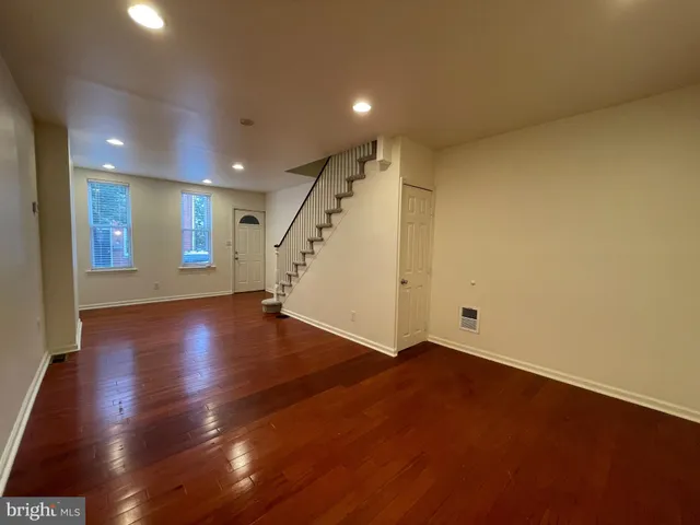 an empty room with wooden floor and staircase
