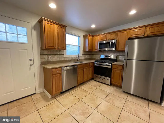 a kitchen with stainless steel appliances granite countertop a refrigerator a sink a stove a microwave and island