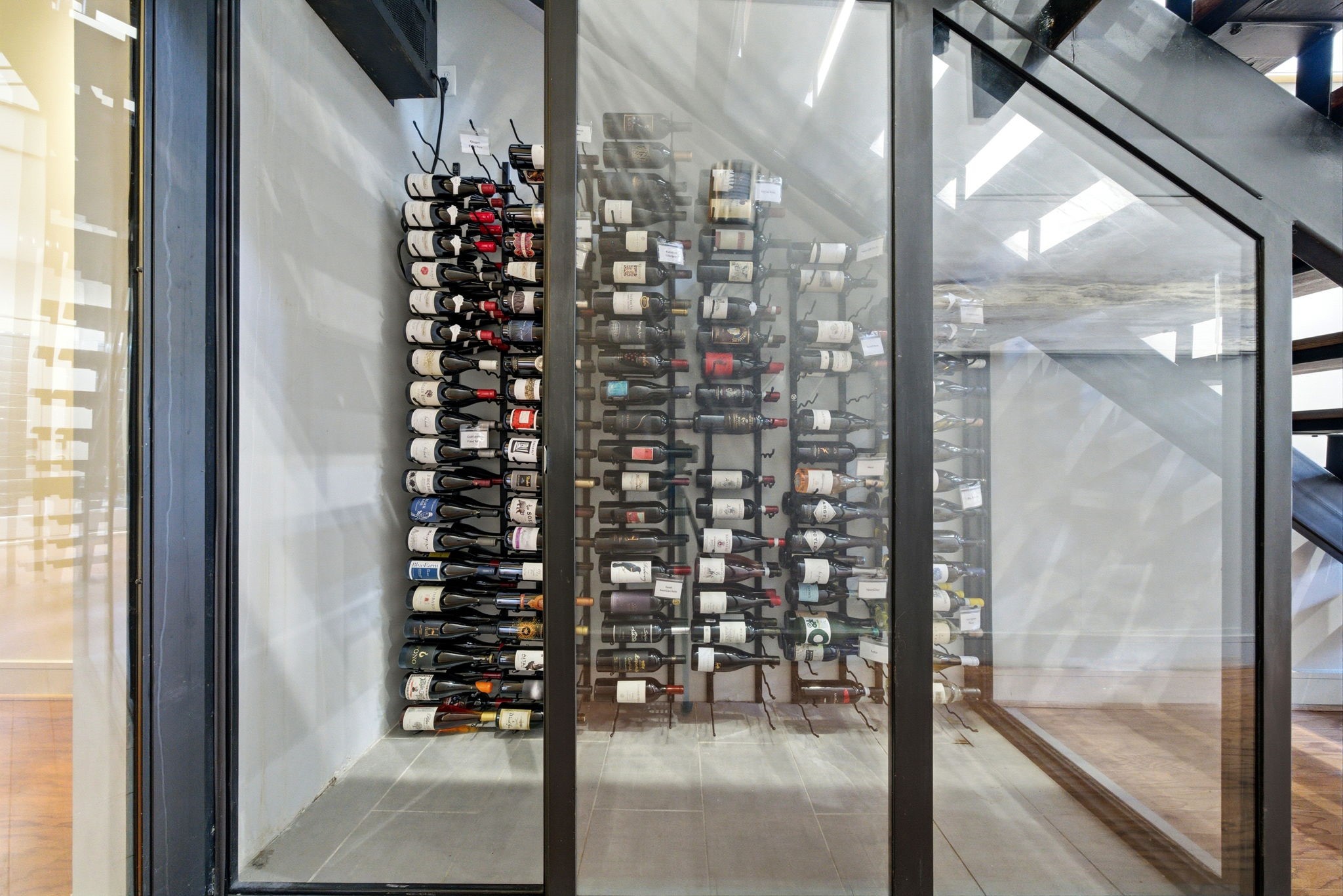 1405 Vermont Street, Unit A Houston, TX 77006 - Photo 25 of 46 High-capacity wine cellar features a climate-controlled, glass-enclosed design tailored for the serious collector. Wall-mounted racks provide a sophisticated display for dozens of bottles beneath the modern floating staircase. This luxury feature highlights the designer finishes and serves as a striking focal point.