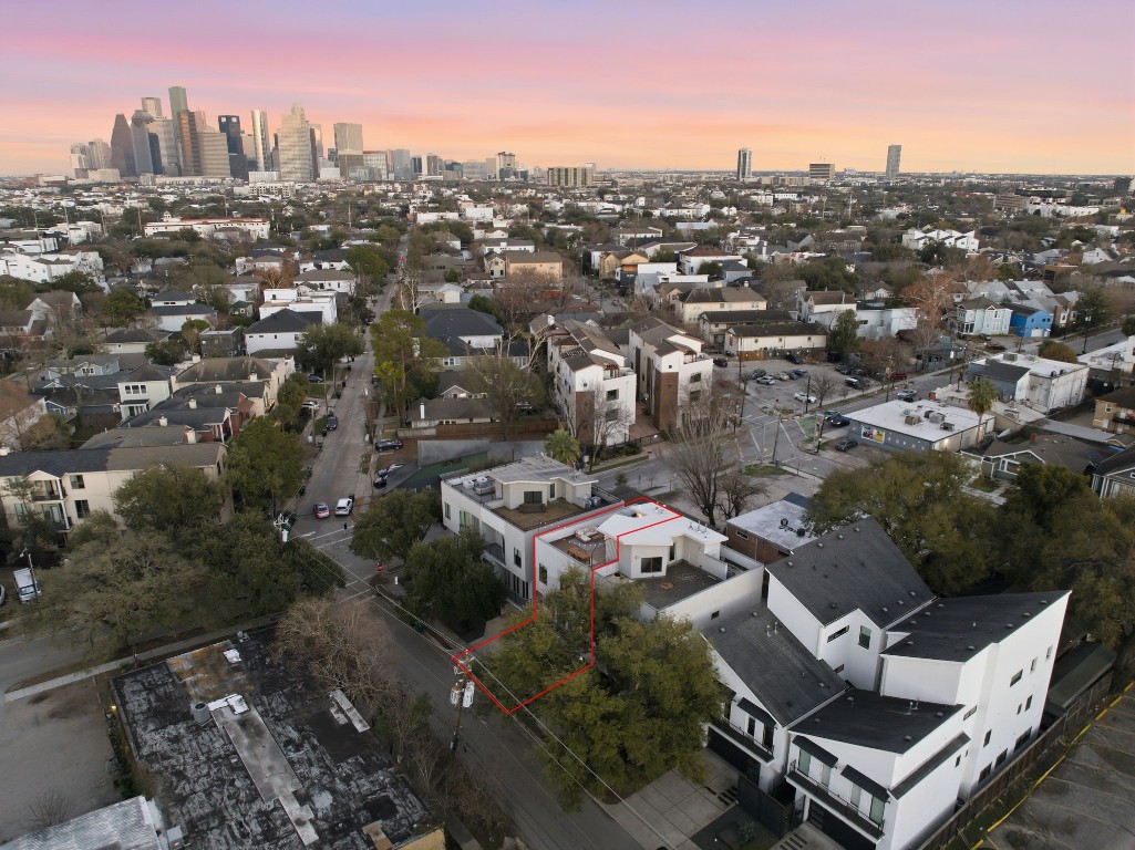 1405 Vermont Street, Unit A Houston, TX 77006 - Photo 42 of 46 Aerial view of 1405 Vermont Street #A highlights a premier Inner Loop location featuring a sprawling rooftop deck and private balconies. This contemporary three-story Bradford Mews residence offers a low-maintenance lifestyle with quick access to Downtown and the Medical Center. Sleek stucco and siding define the exterior, while a private driveway leads to the two-car garage.
