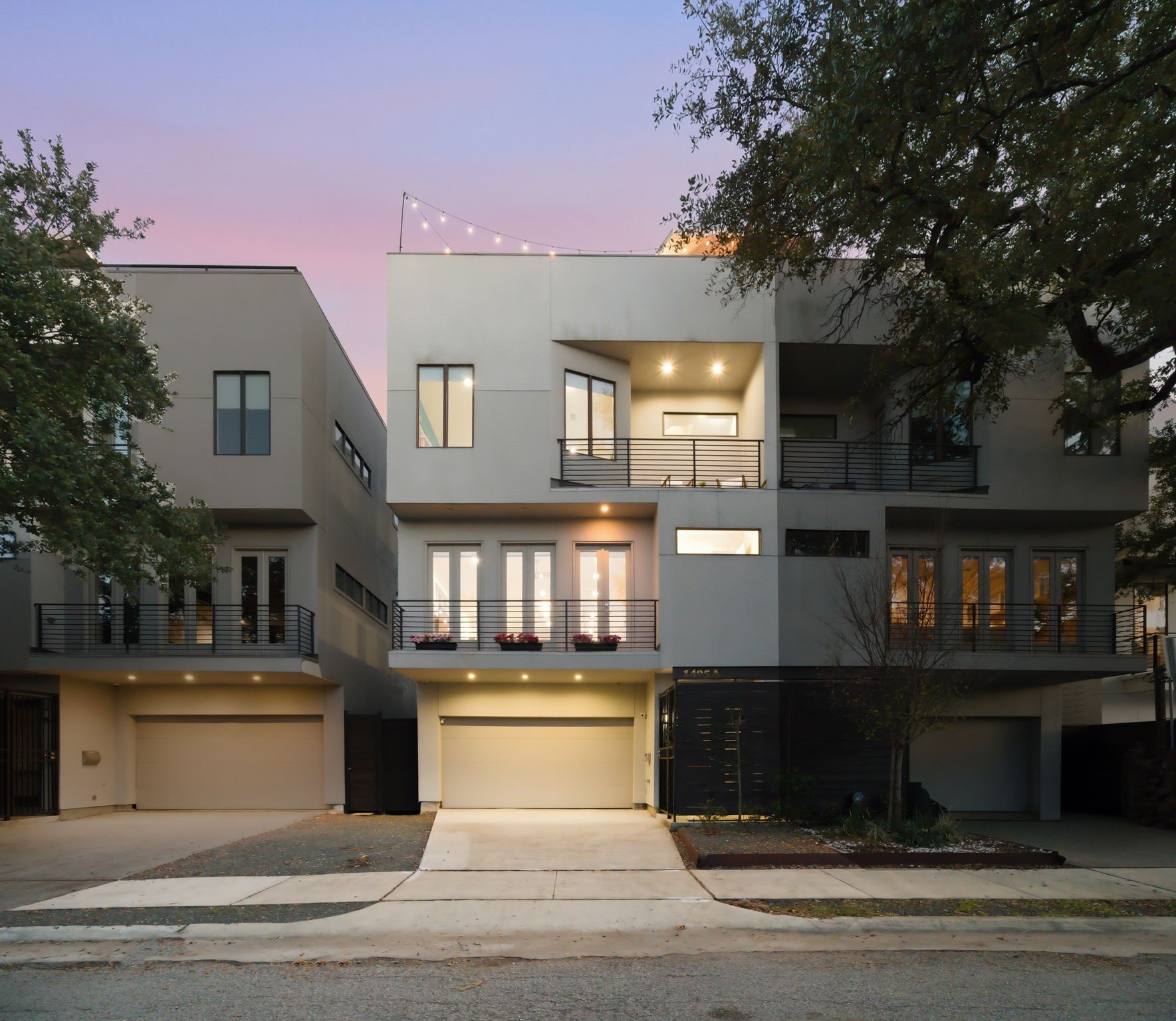 1405 Vermont Street, Unit A Houston, TX 77006 - Photo 6 of 46 Modern stucco and siding define the sophisticated exterior of 1405 Vermont Street #A, a premier three-story Bradford Mews residence. This luxury contemporary home features a private driveway leading to a two-car garage with EV charging capability. Multiple private balconies and a sprawling rooftop deck with string lighting provide exceptional outdoor living spaces minutes from Downtown, Memorial Park, and the Medical Center. Expansive windows and sleek architectural lines showcase a low-maintenance lifestyl
