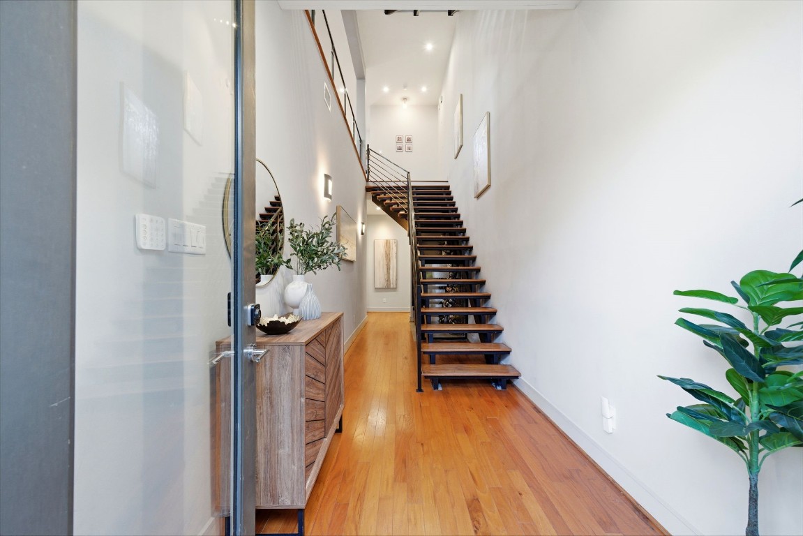 1405 Vermont Street, Unit A Houston, TX 77006 - Photo 8 of 46 Polished hardwoods and soaring ceilings create a dramatic first impression in this light-filled entry, where a modern floating staircase serves as a striking architectural centerpiece. Accent lighting and designer finishes lead the way through the hallway, which provides a seamless connection to the first-floor guest suite and private elevator-ready spaces.