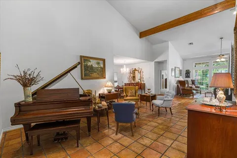 a living room with furniture a piano and a potted plant