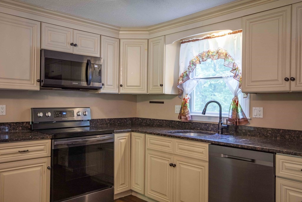 9 Elwood Road Derry, NH 03038 - Photo 18 of 42 a kitchen with stainless steel appliances granite countertop white cabinets and a stove top oven