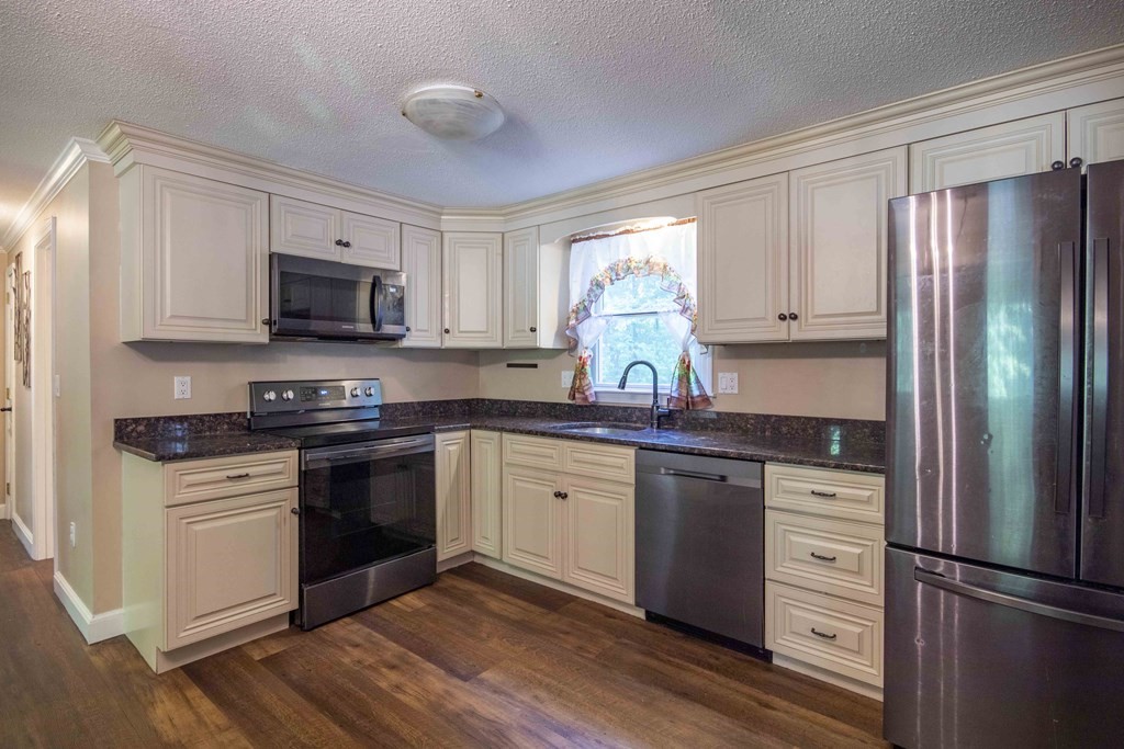 9 Elwood Road Derry, NH 03038 - Photo 23 of 42 a kitchen with granite countertop a refrigerator stove and microwave
