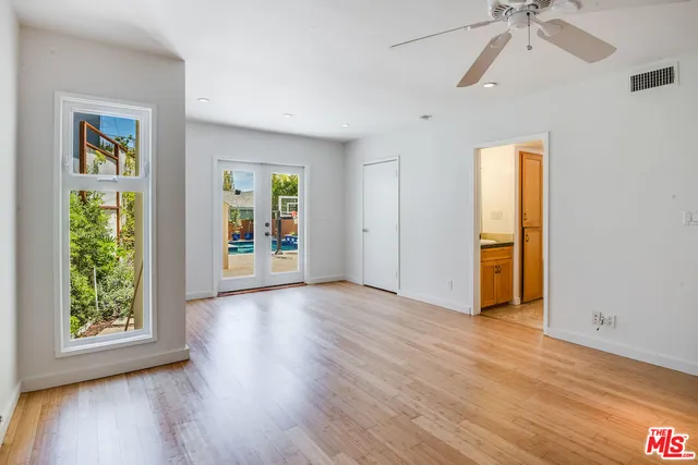 a view of an empty room with a window and wooden floor