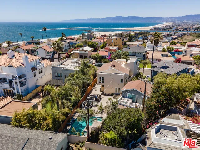 an aerial view of a city with lots of residential buildings and ocean view in back
