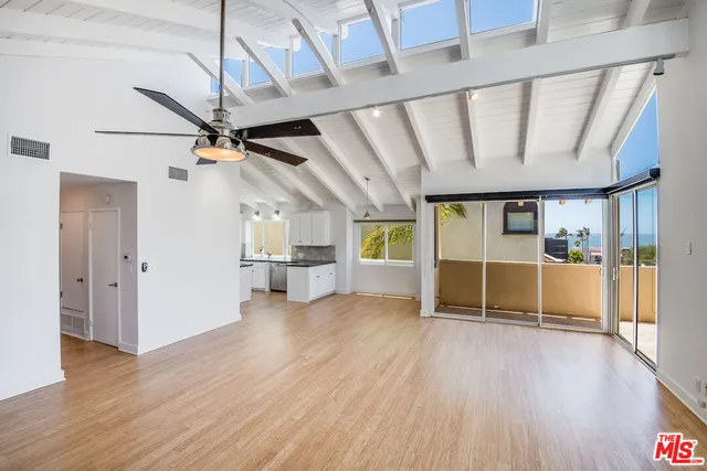 a view of empty room with wooden floor and fan