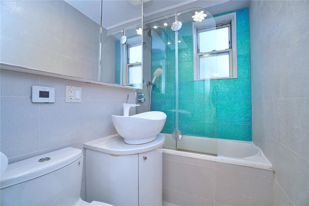 35 Seacoast Terrace, Unit 2N Brooklyn, NY 11235 - Photo 31 of 38 a bathroom with a sink a toilet a mirror and bathtub