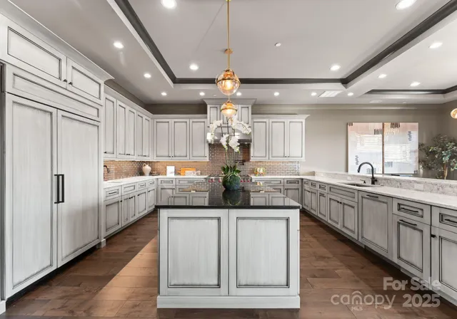 a kitchen with stainless steel appliances granite countertop cabinets a sink and a chandelier