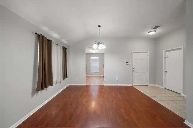 a view of wooden floor and a chandelier in an empty room