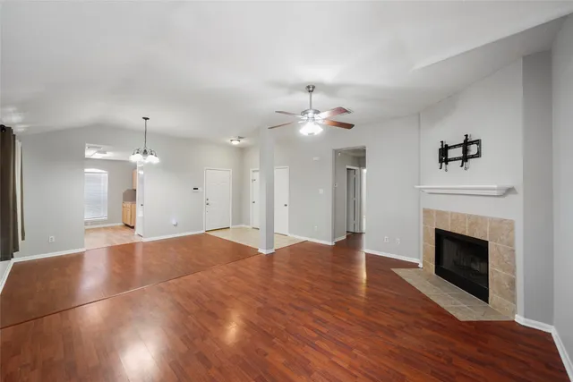 a view of an empty room with wooden floor and fireplace