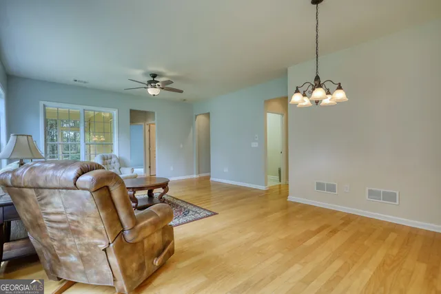 a living room with furniture a chandelier and a dining table
