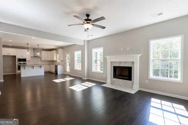 a view of an empty room with wooden floor and a kitchen