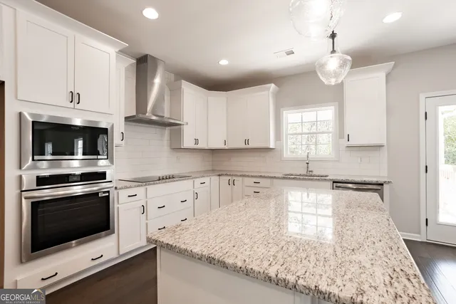 a kitchen with granite countertop a sink stainless steel appliances and white cabinets