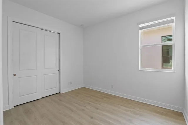 a view of an empty room with wooden floor and closet