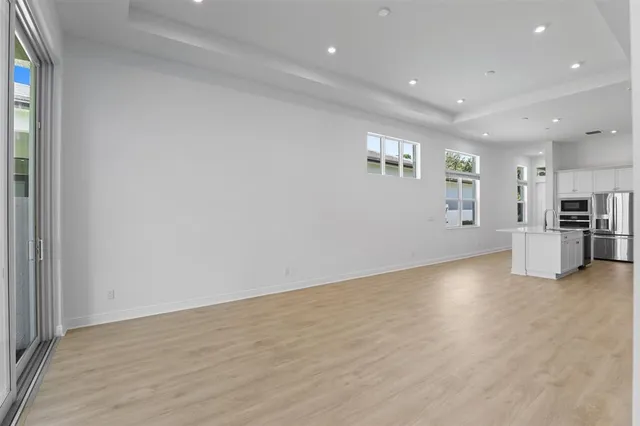 a view of a big room with wooden floor and a kitchen