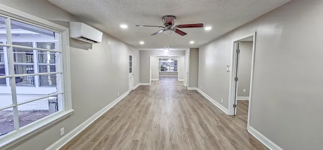a view of a hallway with wooden floor and a ceiling fan