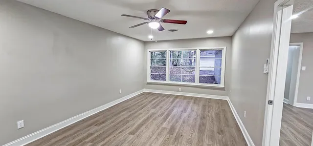 a view of an empty room with a window and wooden floor