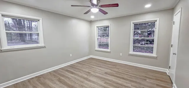 a view of an empty room with a window and wooden floor