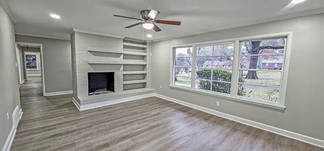 a view of an empty room with a window and wooden floor