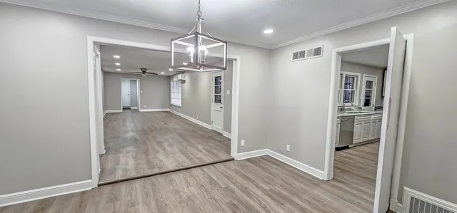 a view of a hallway with wooden floor and a kitchen