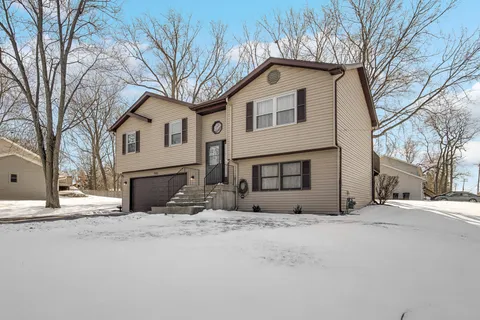 a front view of house with yard covered in snow