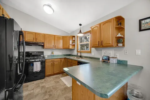 a kitchen with stainless steel appliances granite countertop a sink a stove counter space and cabinets