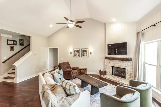 a living room with furniture kitchen view and a wooden floor