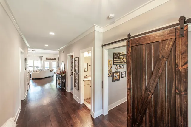 a view of a hallway with wooden floor closet and windows