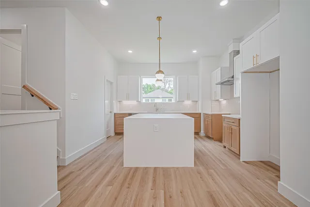 a kitchen with kitchen island wooden floor center island and stainless steel appliances