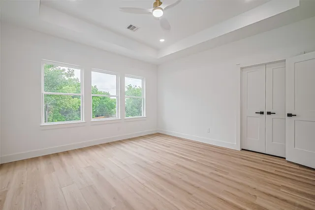 an empty room with wooden floor and windows
