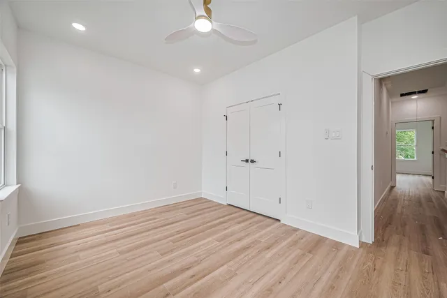 an empty room with wooden floor and a ceiling fan