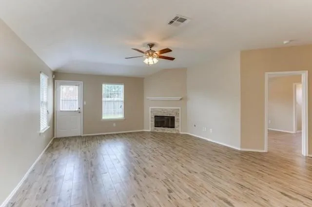 a view of empty room with wooden floor and fireplace