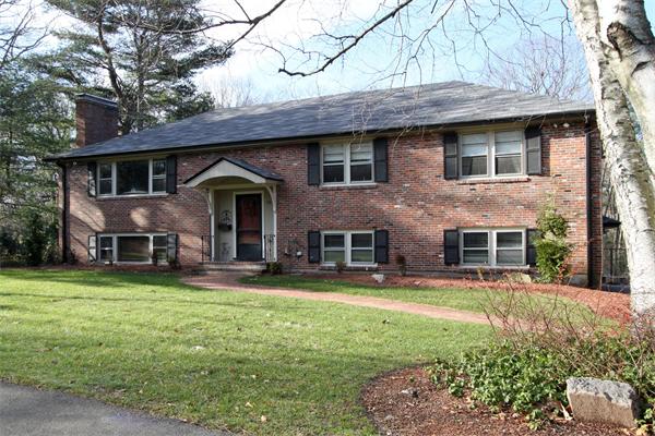 a front view of a house with a garden and trees