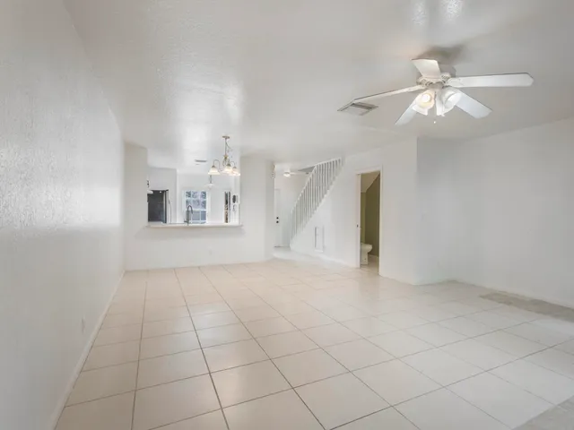 an empty room with chandelier fan and windows