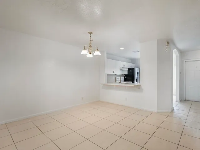 an empty room with kitchen view and window