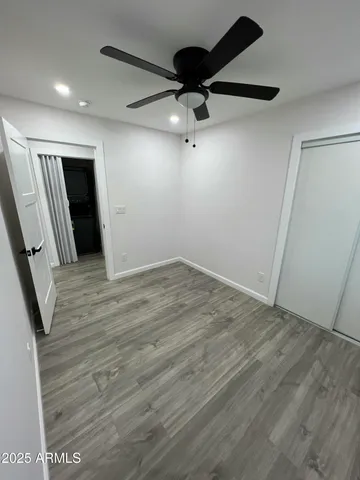 an empty room with wooden floor cabinet and a ceiling fan