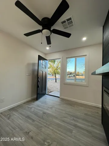 a view of an empty room with a window and wooden floor