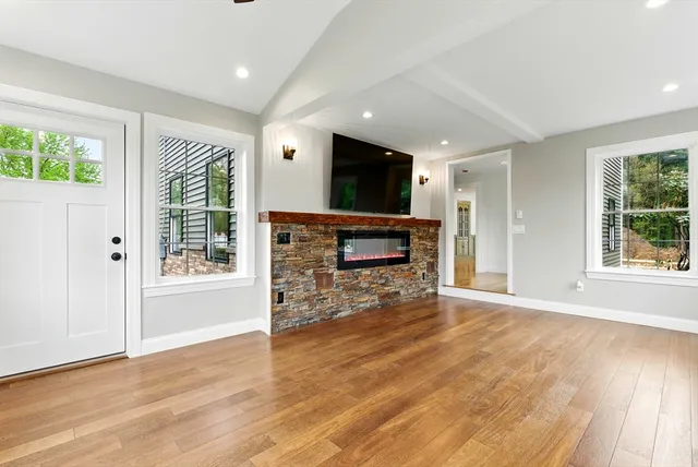 a view of empty room with wooden floor and fireplace