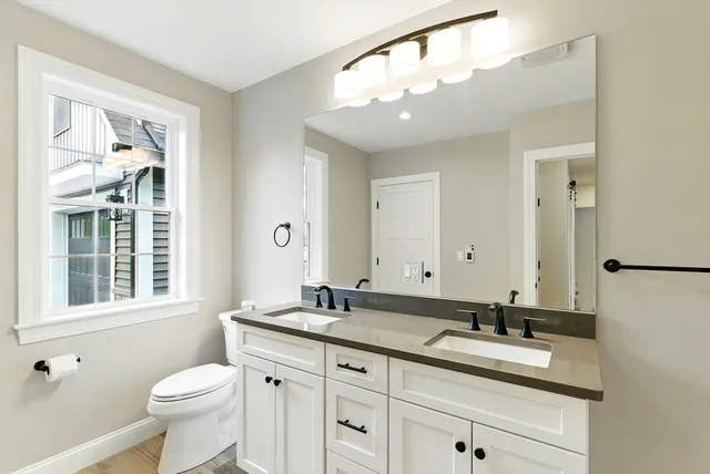a bathroom with a granite countertop toilet sink and mirror