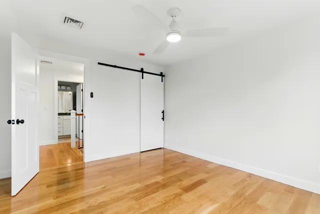 a view of empty room with wooden floor and fan