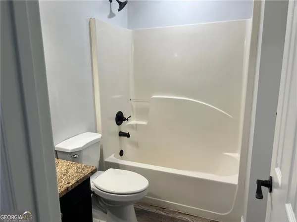 a bathroom with a granite countertop toilet and a bathtub