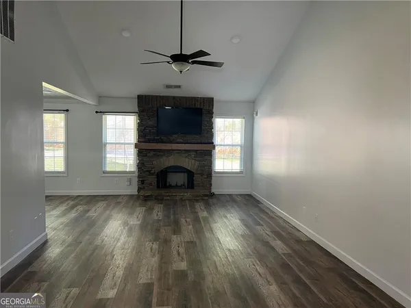 a view of empty room with wooden floor fan and window
