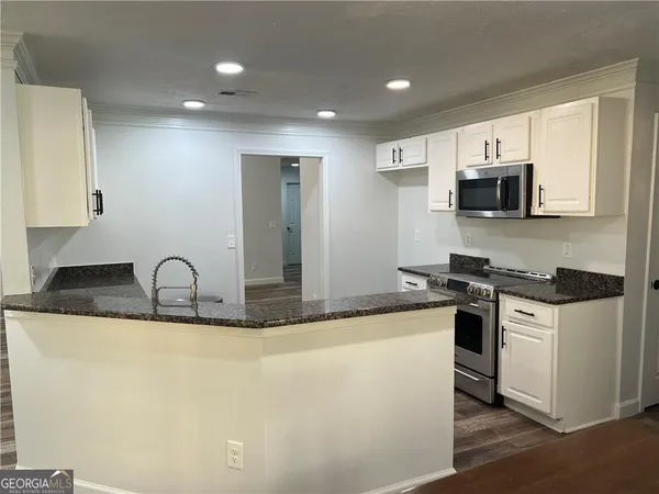 a kitchen with stainless steel appliances granite countertop a refrigerator a stove top oven a sink and dishwasher