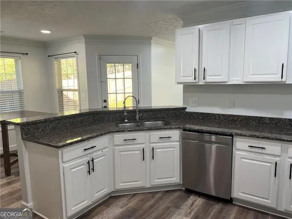 a kitchen with white cabinets and sink