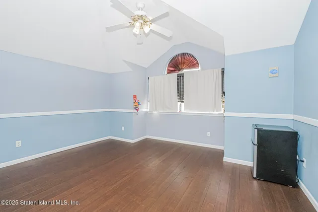 an empty room with wooden floor and fan