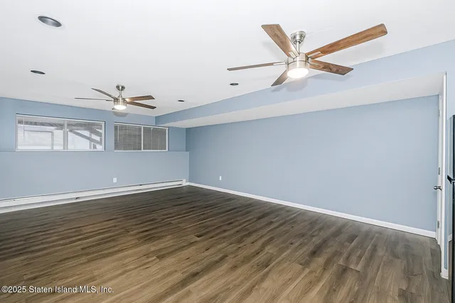 a view of an empty room with wooden floor and a ceiling fan